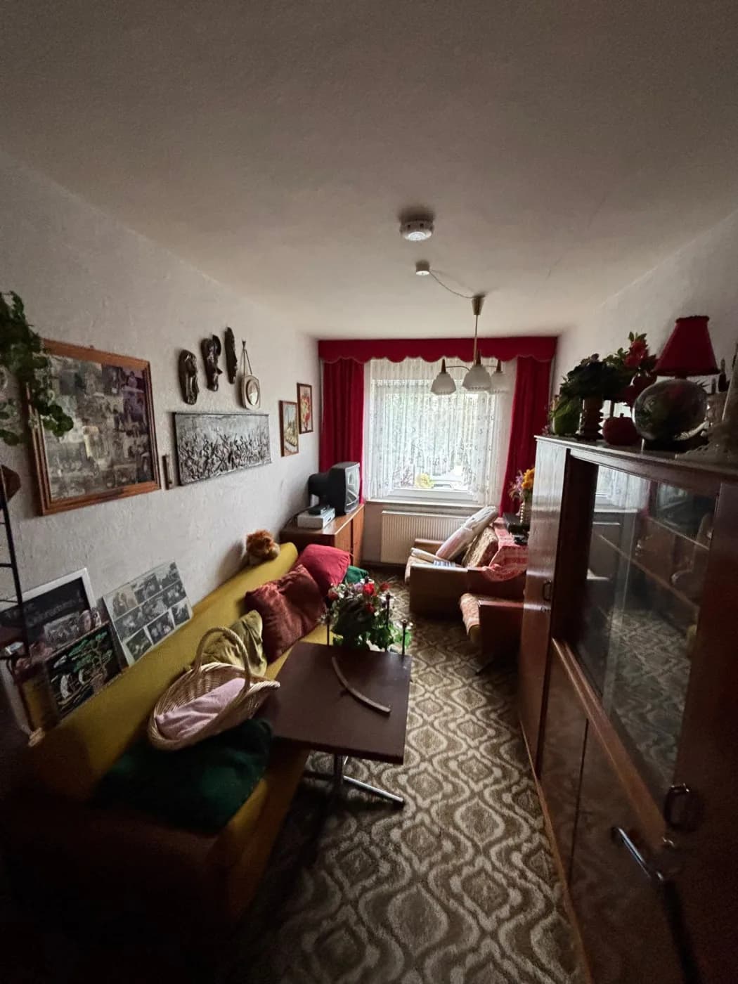 Vollgestelltes Wohnzimmer in einem Haus vor der Entrümpelung, Polstergarnitur und Deko