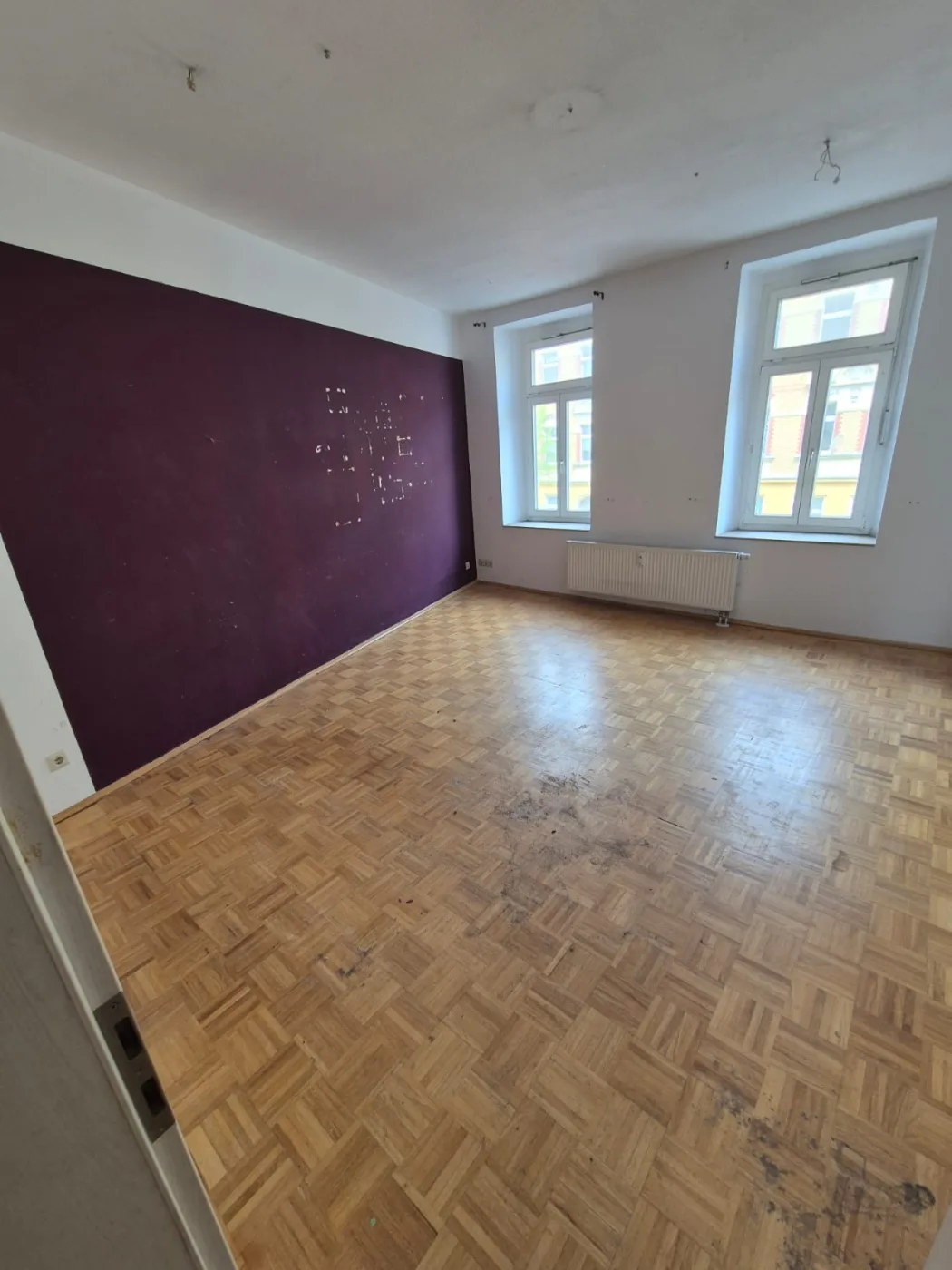 Dasselbe Zimmer leer und besenrein nach der Messie-Räumung, lila Wand, freies Parkett