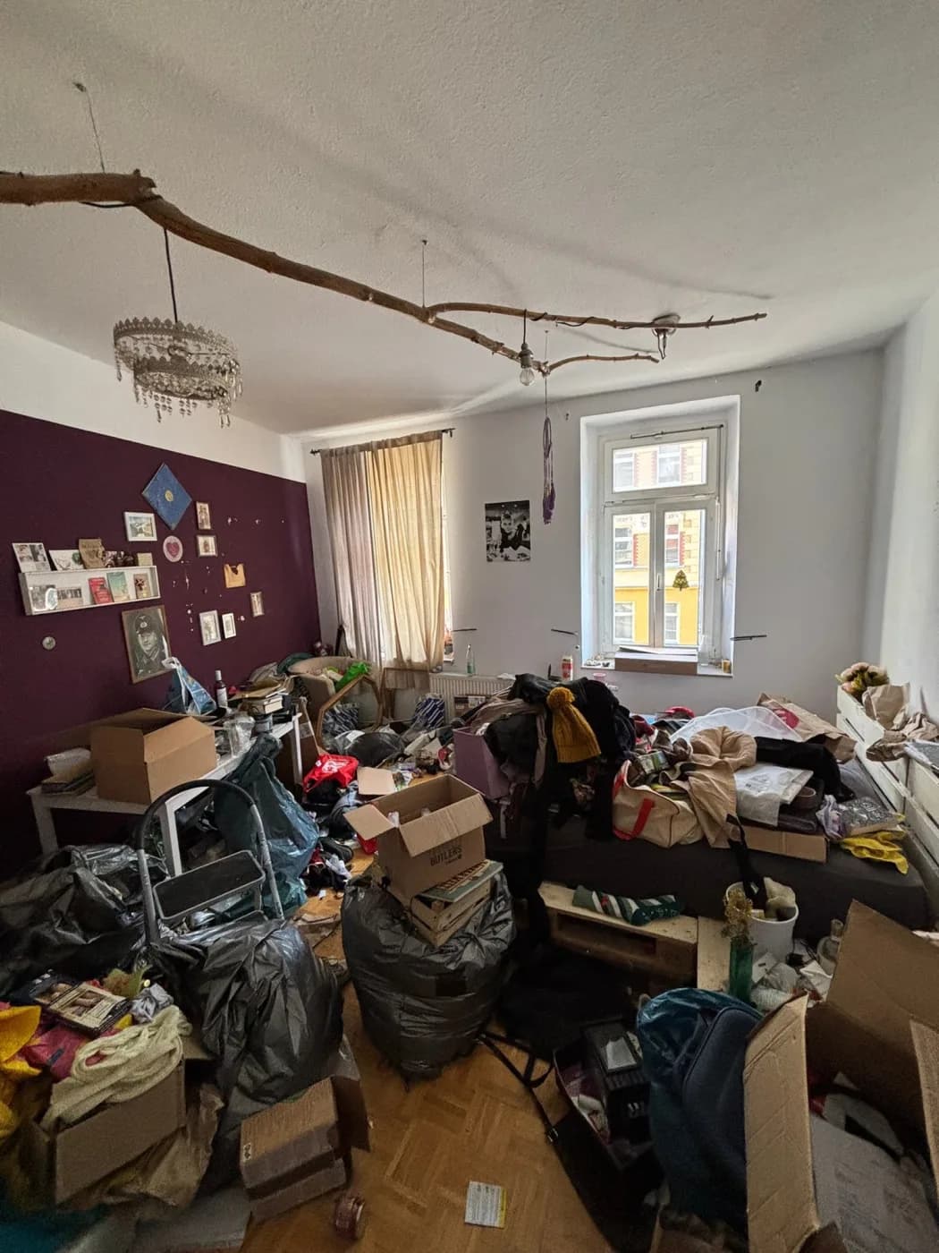 Vollgestelltes Altbauzimmer vor der Räumung, lila Akzentwand