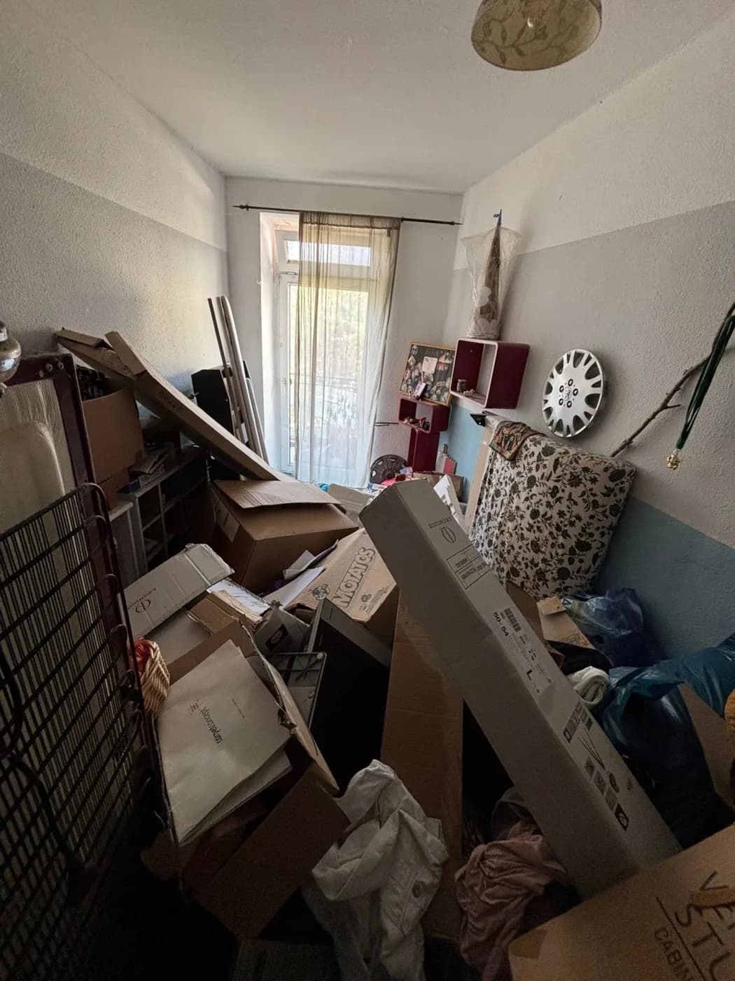 Zimmer mit Kartons und Gerümpel vor der Räumung, blau-weisse Wand