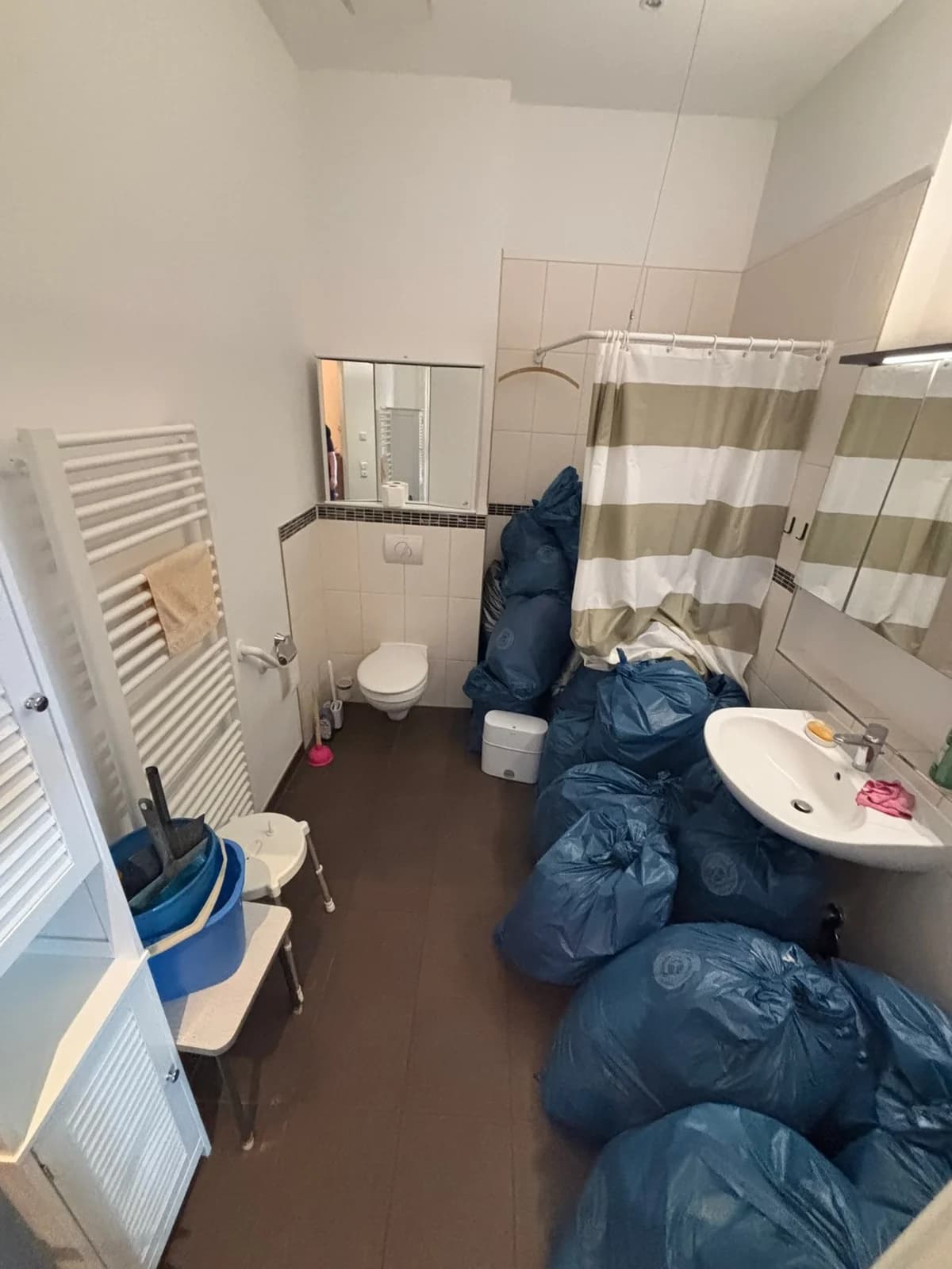 Badezimmer bei der Übernahme, Boden voller blauer Müllsäcke vor der Endreinigung